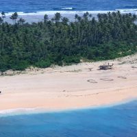 This handout photo taken on August 2, 2020 and received on August 4 from the Australian Defence Force shows an Australian Army ARH Tiger helicopter landing near the letters "SOS" (C) on a beach on Pikelot Island where three men were found in good condition after being missing for three days. - Three Micronesian sailors stranded on a tiny island in the remote Western Pacific were rescued after Australian and US warplanes spotted a giant "SOS" they had scrawled on the beach, officials said. (Photo by Handout / Australian Defence Force / AFP) / RESTRICTED TO EDITORIAL USE - MANDATORY CREDIT "AFP PHOTO / AUSTRALIAN DEFENCE FORCE" - NO MARKETING - NO ADVERTISING CAMPAIGNS - DISTRIBUTED AS A SERVICE TO CLIENTS