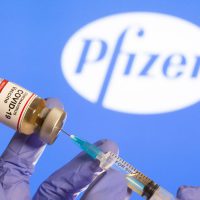 Mulher segura frasco rotulado como de vacina contra Covid-19 em frente a logo da Pfizer em foto de ilustração
30/10/2020 REUTERS/Dado Ruvic